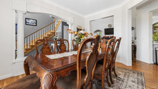 dining area with wood-type flooring, crown molding, and ornate columns