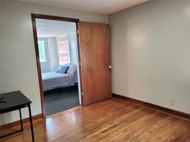 empty room with a textured ceiling, baseboards, and wood finished floors