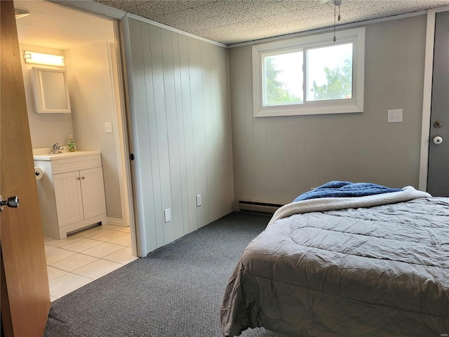 bedroom with light carpet, light tile patterned floors, baseboard heating, and a sink