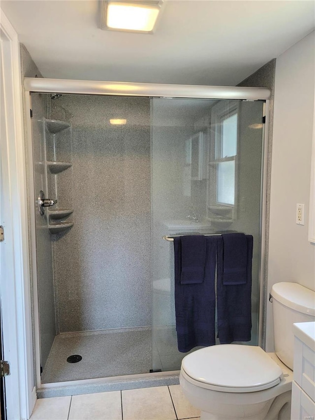 bathroom featuring toilet, tile patterned flooring, and a shower stall