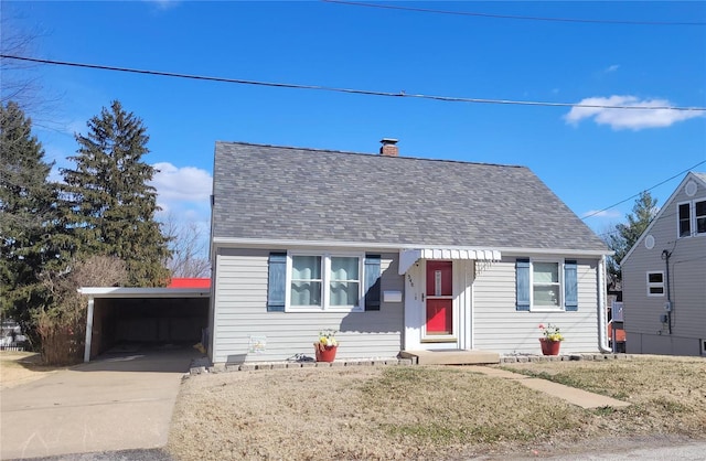 view of front of home with driveway, an attached carport, roof with shingles, and a chimney