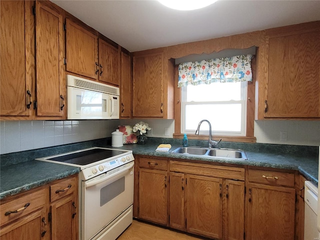 kitchen featuring tasteful backsplash, white appliances, a sink, and brown cabinets