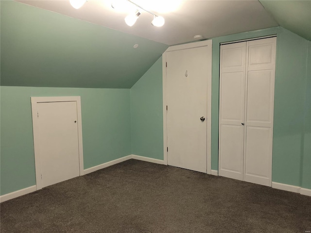 bonus room featuring vaulted ceiling, dark carpet, and baseboards