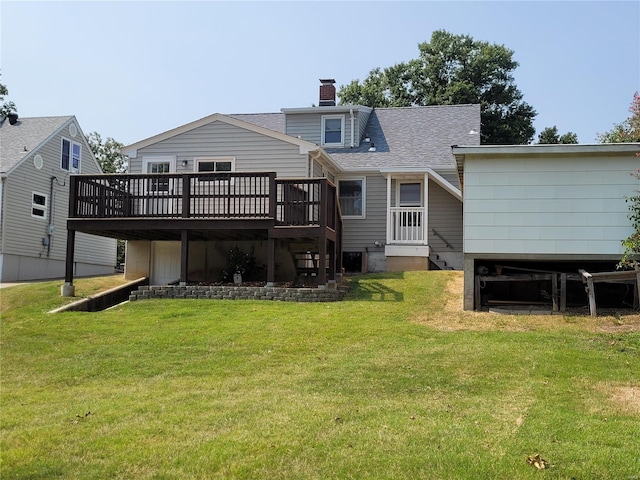 back of house featuring a deck, a yard, roof with shingles, and a chimney