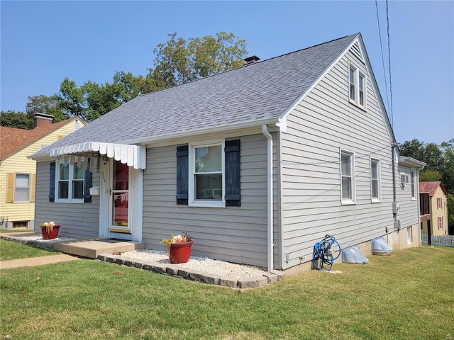 bungalow-style house with a shingled roof, a chimney, and a front lawn