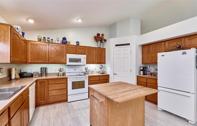 kitchen with a kitchen island, lofted ceiling, white appliances, and light hardwood / wood-style flooring