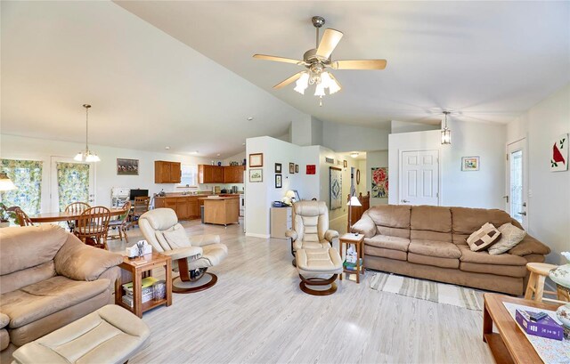 living room featuring ceiling fan with notable chandelier and light hardwood / wood-style flooring