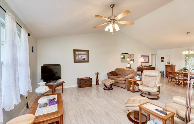 living room with light wood-type flooring, ceiling fan with notable chandelier, lofted ceiling, and plenty of natural light