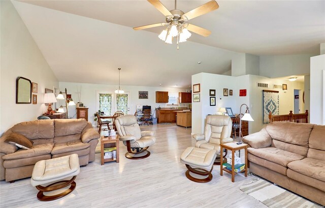 living room featuring vaulted ceiling, light hardwood / wood-style floors, and ceiling fan