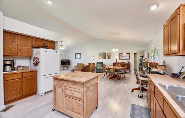 kitchen featuring white refrigerator, light wood-type flooring, lofted ceiling, decorative light fixtures, and ceiling fan with notable chandelier