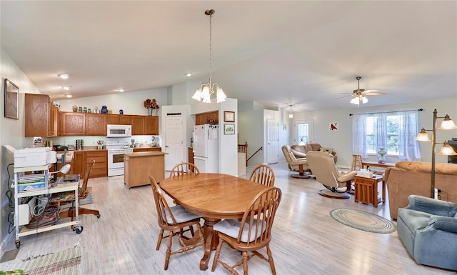 dining space featuring ceiling fan with notable chandelier, light wood-type flooring, and vaulted ceiling