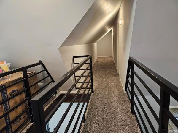 corridor with dark carpet and vaulted ceiling