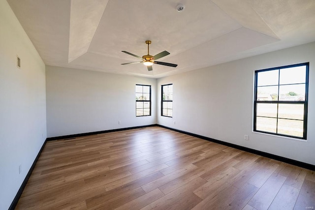 spare room featuring a raised ceiling, ceiling fan, and hardwood / wood-style floors