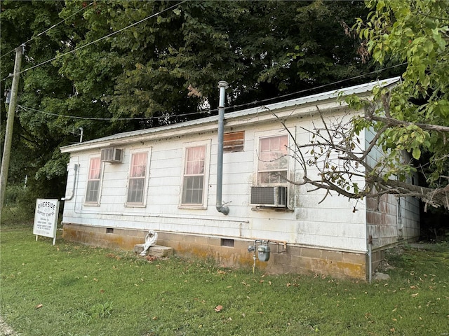 view of side of home with a yard, a wall mounted AC, crawl space, metal roof, and cooling unit