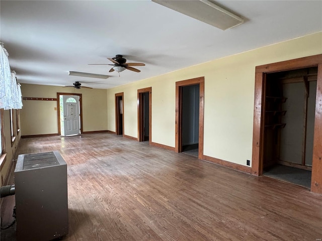 unfurnished living room featuring ceiling fan, wood finished floors, and baseboards