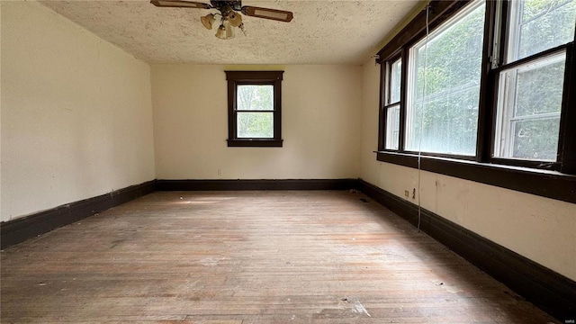 unfurnished room with a textured ceiling, a healthy amount of sunlight, ceiling fan, and light wood-type flooring