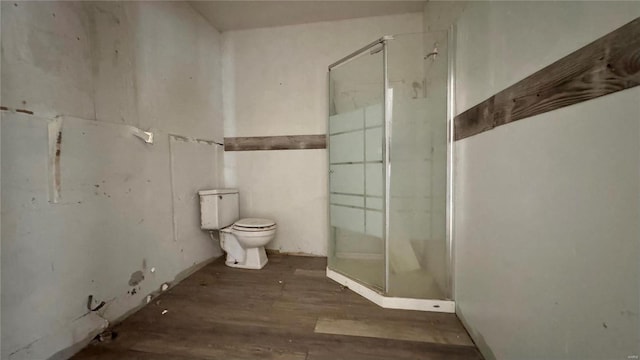 bathroom with toilet, hardwood / wood-style floors, and a shower