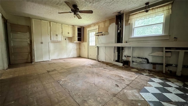 miscellaneous room with ceiling fan and a textured ceiling