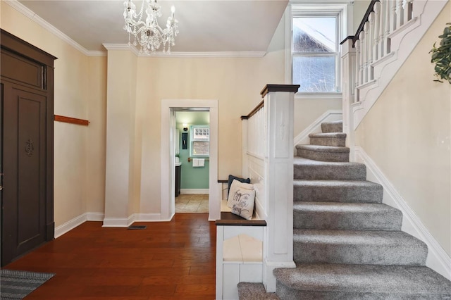 entrance foyer with dark hardwood / wood-style flooring, ornamental molding, and an inviting chandelier