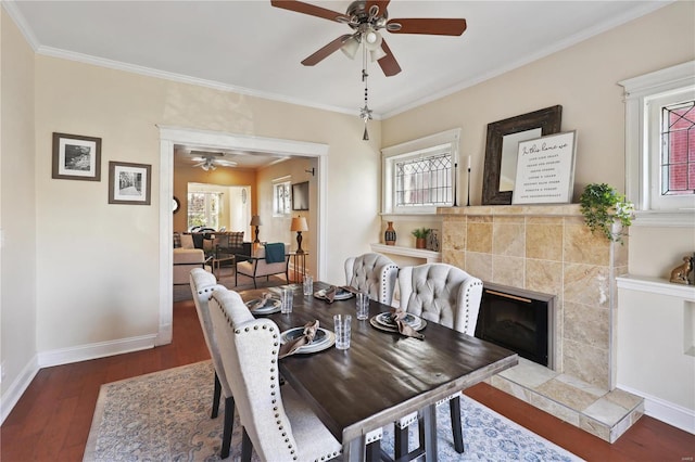 dining space with dark hardwood / wood-style floors, ceiling fan, crown molding, and a tile fireplace