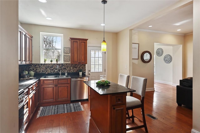 kitchen with decorative backsplash, stainless steel appliances, dark wood-type flooring, sink, and a center island