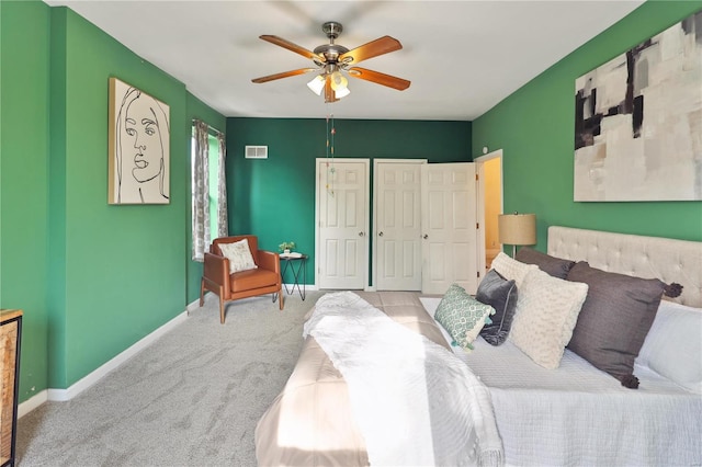 carpeted bedroom with ceiling fan and multiple closets