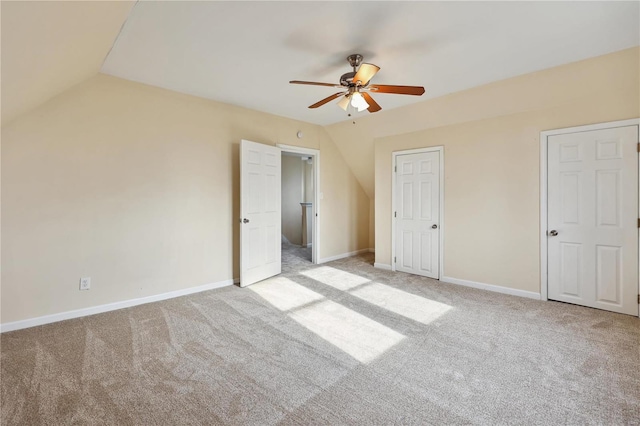 unfurnished bedroom featuring light colored carpet, vaulted ceiling, and ceiling fan