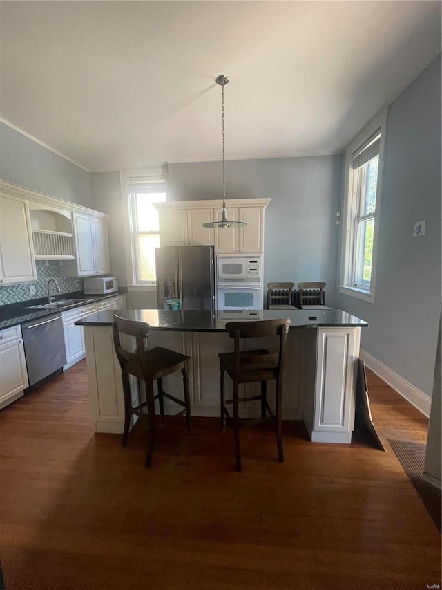 kitchen featuring a kitchen island, dark hardwood / wood-style floors, pendant lighting, and appliances with stainless steel finishes