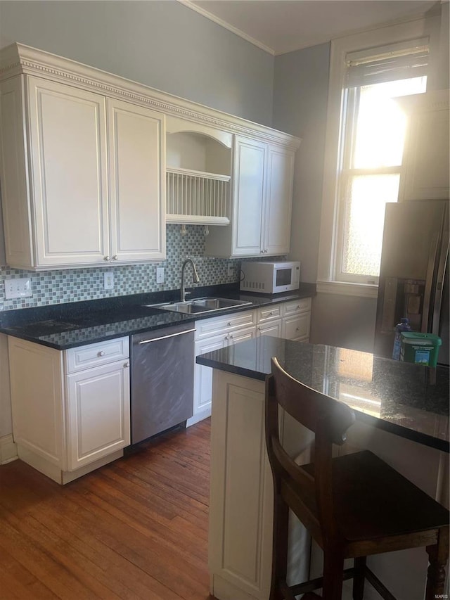 kitchen featuring stainless steel appliances, sink, dark hardwood / wood-style floors, white cabinets, and decorative backsplash