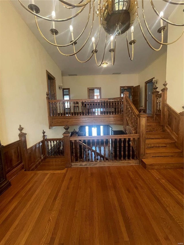 staircase featuring an inviting chandelier and hardwood / wood-style floors