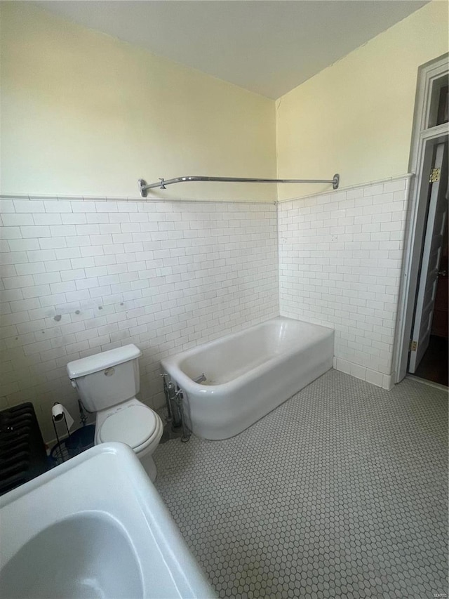 bathroom featuring toilet and tile walls