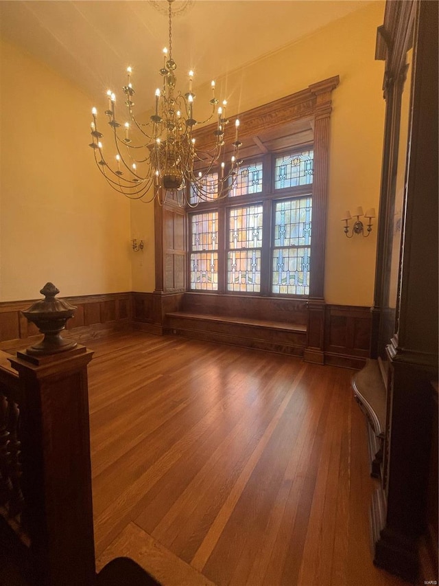 unfurnished dining area featuring wooden walls, a chandelier, and wood-type flooring