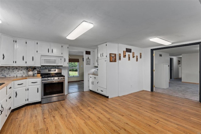 kitchen featuring white cabinetry, light hardwood / wood-style flooring, stainless steel gas range oven, and tasteful backsplash