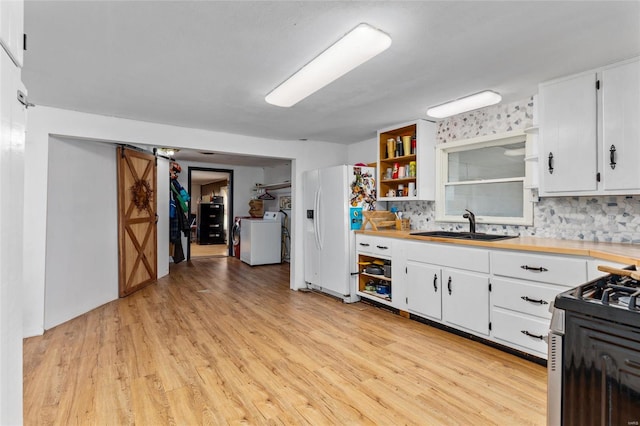 kitchen with washer / clothes dryer, light hardwood / wood-style floors, white cabinetry, and sink