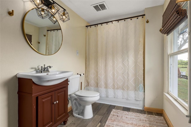 full bathroom featuring an inviting chandelier, hardwood / wood-style floors, toilet, shower / tub combo with curtain, and vanity