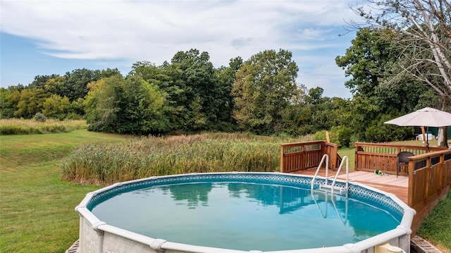 view of swimming pool featuring a lawn and a deck