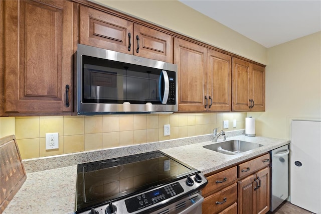 kitchen with sink, light stone countertops, stainless steel appliances, and backsplash