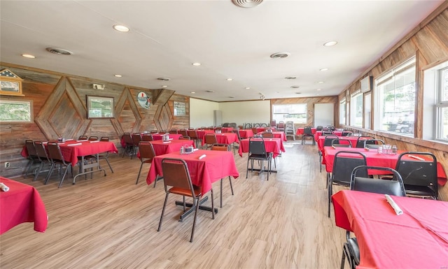 dining space featuring hardwood / wood-style flooring and wooden walls