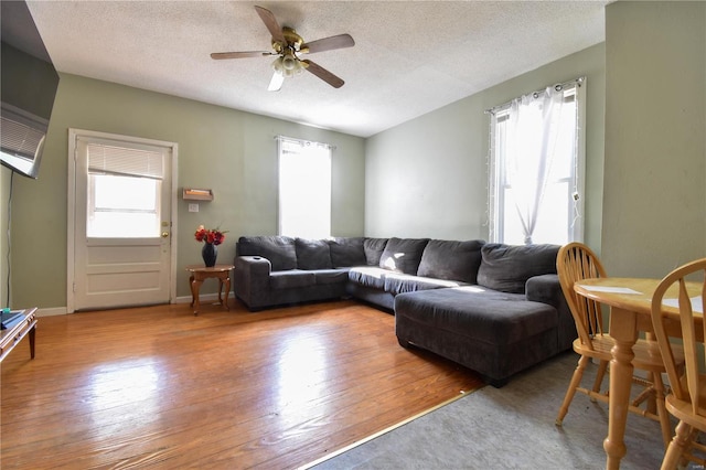 living room featuring light hardwood / wood-style floors, ceiling fan, and a textured ceiling