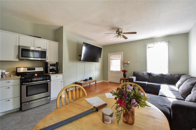 kitchen featuring stainless steel appliances, ceiling fan, white cabinets, and a textured ceiling