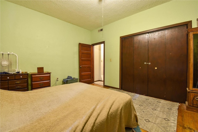 bedroom featuring light hardwood / wood-style floors, a textured ceiling, and a closet