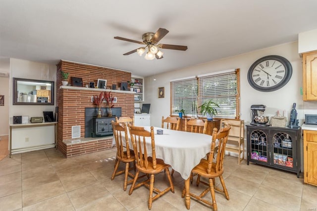 tiled dining space with ceiling fan and a fireplace