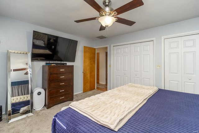 carpeted bedroom with two closets and ceiling fan