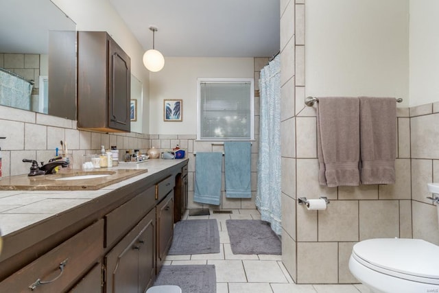 bathroom featuring toilet, tile patterned flooring, vanity, decorative backsplash, and tile walls