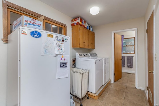 clothes washing area featuring light tile patterned floors, cabinets, and washer and dryer