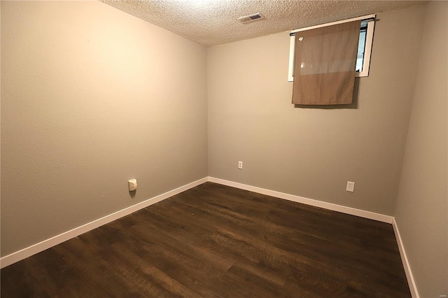 spare room featuring a textured ceiling and dark wood-type flooring