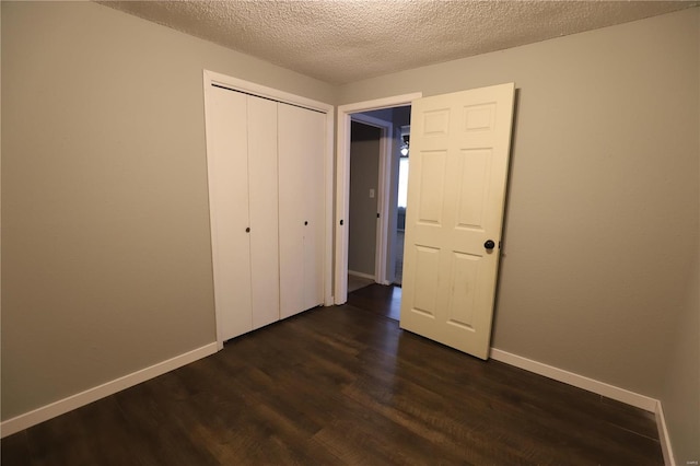 unfurnished bedroom featuring a textured ceiling, a closet, and dark hardwood / wood-style flooring