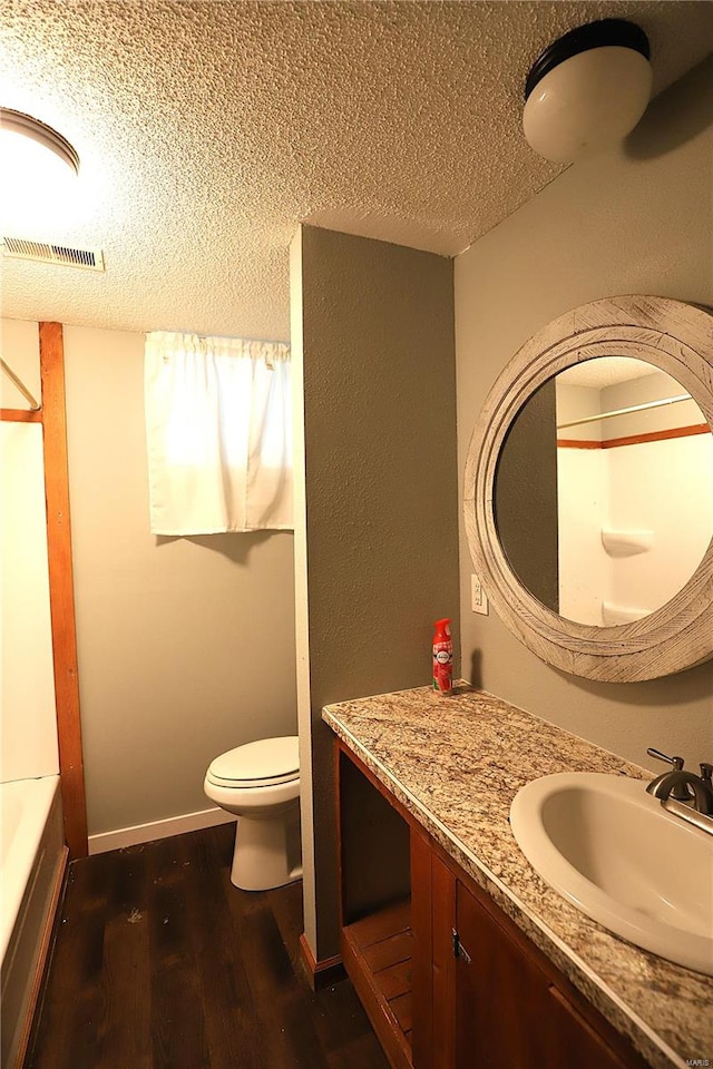 full bathroom with vanity, a textured ceiling, hardwood / wood-style flooring, plus walk in shower, and toilet