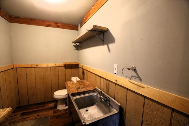 bathroom featuring sink, wood walls, hardwood / wood-style flooring, and toilet