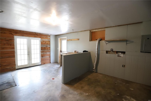 kitchen featuring wood walls, electric panel, concrete floors, and french doors